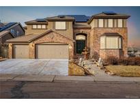 Two-story home featuring a three-car garage, solar panels, fountain, brick accents, and mature landscaping at 301 Amethyst Way, Superior, CO 80027