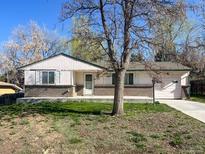 Single-story home showcasing brick detailing, an attached garage, and a well-maintained front yard at 10067 W 68Th Pl, Arvada, CO 80004