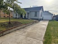 Charming home with well-manicured lawn, brick accents, and a long concrete driveway leading to a detached garage at 2728 N Yates St, Denver, CO 80212