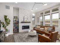 Bright living room boasts modern fireplace with white brick, hardwood floors, and ample natural light at 11027 Sunshimmer Cir, Parker, CO 80134