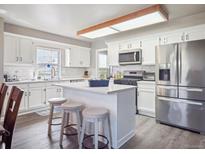 Bright eat-in kitchen with an island, white cabinetry, stainless appliances, and modern lighting at 10961 Main Range Trl, Littleton, CO 80127