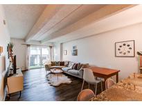 Bright living room with a large sofa, wood floors, and a glass sliding door at 1265 Race St # 408, Denver, CO 80206