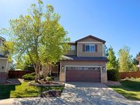 Charming two-story home featuring a well-manicured lawn, mature trees, and an attached two-car garage at 10358 Kelliwood Way, Highlands Ranch, CO 80126