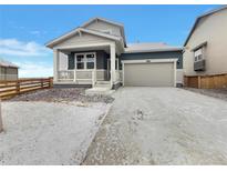 Charming single-Gathering home with a two-car garage, covered porch and wintry landscape at 12892 E 99Th Pl, Commerce City, CO 80022