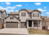 Charming two-story home with a three-car garage, stone accents, and a well-manicured front yard at 13034 Bridge View Ln, Parker, CO 80134