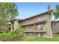 Three-story condo building featuring red entry doors and wood railings overlooking manicured landscaping at 695 Manhattan Dr # 109, Boulder, CO 80303