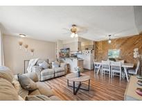 Open-concept living area featuring a wood accent wall, wood flooring, and a comfortable seating arrangement at 1272 S Uvalda St, Aurora, CO 80012
