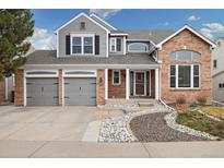 Charming two-story home featuring a brick facade, gray siding, attached garages, and manicured front yard at 787 Huntington Pl, Highlands Ranch, CO 80126
