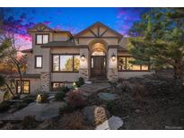 Stunning two-story home with a stone archway and wood door, complemented by manicured landscaping and stone pathway at 32569 El Diente Ct, Evergreen, CO 80439