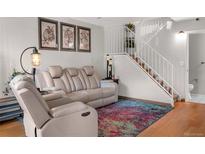 Comfortable living room with a reclining sofa and chair, plus white staircase and colorful rug at 2557 S Dover St # 68, Lakewood, CO 80227