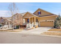 Charming tan two-story home with a covered front porch, white railings, and an attached two-car garage at 705 Sundance Cir, Erie, CO 80516