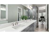 Bright bathroom featuring a double sink vanity with a white countertop, gray cabinets, and a large mirror at 5839 Hay Market Trl, Parker, CO 80134