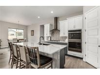 Modern kitchen features a large island with seating and white cabinets with stainless steel appliances at 5839 Hay Market Trl, Parker, CO 80134