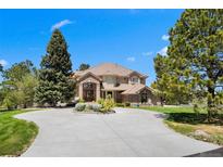 Elegant two-story home boasts a circular driveway, lush landscaping, and a welcoming entrance at 7645 Fox Creek Trl, Franktown, CO 80116