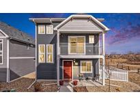 Charming two-story home with red door, balcony, and chairs on the front porch offers curb appeal at 5390 N Argonne St, Denver, CO 80249