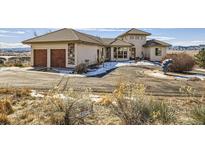 Inviting stucco home with two-car garage and circular driveway situated in scenic snowy landscape at 8611 Coachlight Way, Littleton, CO 80125