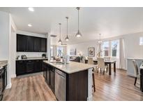 Open-concept kitchen boasts an island with granite countertops and dark wood cabinets at 9080 Fig St, Arvada, CO 80005