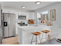Bright kitchen with white cabinetry, stainless steel appliances, and a quartz countertop island with breakfast bar at 9658 W Chatfield Ave # D, Littleton, CO 80128