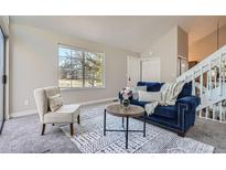 Bright living room featuring a navy couch, modern decor, and a large window offering ample natural light at 1013 S Zeno Way, Aurora, CO 80017