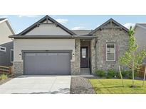 Charming home featuring a stone and siding facade, with a two-car garage and beautifully landscaped front yard at 5905 S Platte Canyon Dr, Littleton, CO 80123