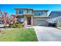 Charming two-story home with a well-manicured lawn, a driveway, and a beautiful flowering tree in the front yard at 26909 E Cedar Ave, Aurora, CO 80018