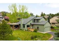 Beautiful exterior of home with green siding, covered porch, manicured lawn and attached garage at 3257 Sun Ridge Ln, Evergreen, CO 80439
