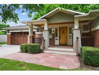 Inviting covered front porch with beautiful wood door, stone walkway, and lush landscaping at 2957 S York St, Denver, CO 80210