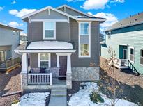 Charming two-story home showcasing a covered porch, stone accents, and a well-maintained front yard, creating an inviting curb appeal at 470 Kiowa Ave, Bennett, CO 80102