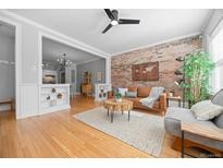 Inviting living room featuring a stylish brick wall, hardwood floors, and an open layout to the kitchen at 529 E 14Th Ave # 10, Denver, CO 80203