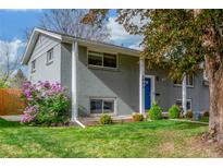 The lush front lawn, garden and brick facade leading up to the covered entry at 3841 W Quinn Pl, Denver, CO 80236