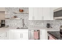 Bright kitchen with white cabinets, stainless steel appliances, herringbone tile backsplash, and quartz countertops at 3841 W Quinn Pl, Denver, CO 80236