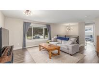 Bright living room with large window, wood floors, comfortable seating, and modern lighting at 3841 W Quinn Pl, Denver, CO 80236