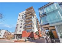 Modern condo building with large balconies, steel accents and brickwork against a clear blue sky at 1475 Delgany St # 807, Denver, CO 80202