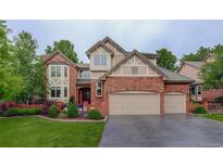 Charming two-story brick home with a well-manicured lawn and a spacious three-car garage at 11904 W Auburn Dr, Denver, CO 80228