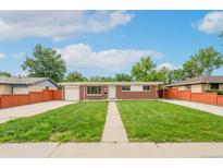 Charming single-story brick home featuring a well-manicured lawn and inviting walkway under a bright blue sky at 3216 Revere St, Aurora, CO 80011
