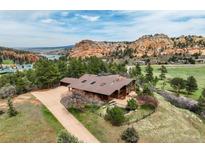 Stunning aerial view showcasing the home's serene setting with mountain views, mature trees, and lush lawn at 5565 Osage Way, Larkspur, CO 80118