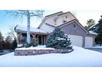 Two-story home with stone accents and snowy landscaping at 76 Buckthorn Dr, Littleton, CO 80127