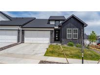 Modern townhome with a dark exterior, a two-car garage, and newly installed landscaping at 8244 S Queen St, Littleton, CO 80127