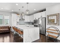 Bright kitchen boasts an island with quartz countertop and stainless steel appliances at 15732 E Broncos Pl, Englewood, CO 80112