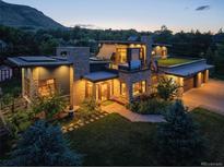 Stunning modern home with stone accents, solar panels, a green roof, and lush landscaping at dusk at 5123 Quaker St, Golden, CO 80403