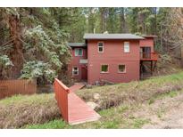 Charming cabin-style home featuring a red-toned exterior and surrounded by lush greenery and mature trees at 17422 N Canyon Rd, Littleton, CO 80127