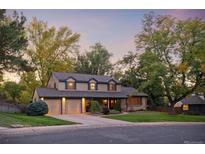 Two-story house with attached two-car garage, landscaping, and a tree-lined street at 7027 S Madison Way, Centennial, CO 80122