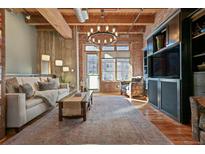 Bright living room with exposed brick, wooden beams, a decorative rug, and large windows with natural light at 2960 Inca St # 115, Denver, CO 80202