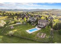 Expansive aerial view of a beautiful property with a pool and large yard, mountains in the distance at 7624 Russell Ct, Arvada, CO 80007