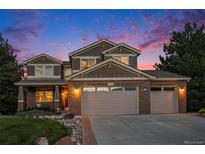 Beautiful two-story home with a three-car garage and brick accents, illuminated by warm exterior lighting at 7624 Russell Ct, Arvada, CO 80007