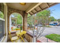 Inviting front porch featuring a yellow table set, brick archway, and neighborhood view at 1217 E 26Th Ave, Denver, CO 80205