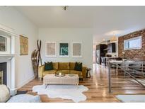 Comfortable living room with hardwood floors, exposed brick, and open view to the kitchen at 1217 E 26Th Ave, Denver, CO 80205