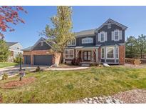 Elegant two-story home with brick and siding exterior, mature landscaping, and an attached three-car garage at 404 Yarrow Pl, Castle Pines, CO 80108