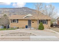 Charming brick home featuring a well-maintained front yard, a mountain in the background, and mature trees at 217 Ford St, Golden, CO 80403