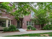 Inviting two-story red brick home featuring lush landscaping and a welcoming front entrance at 9165 Kornbrust Dr, Lone Tree, CO 80124